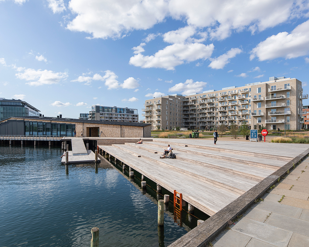 Teglholm Brygge, flere personer nyder solskinnet på trækonstruktionen